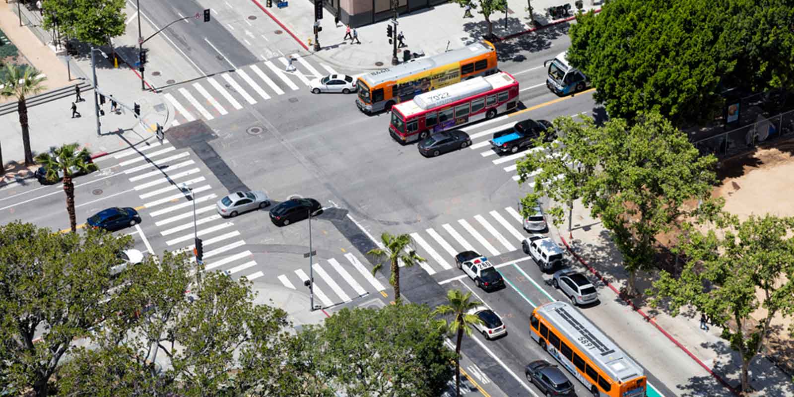 Aerial view of cars and buses driving through four-way intersection.