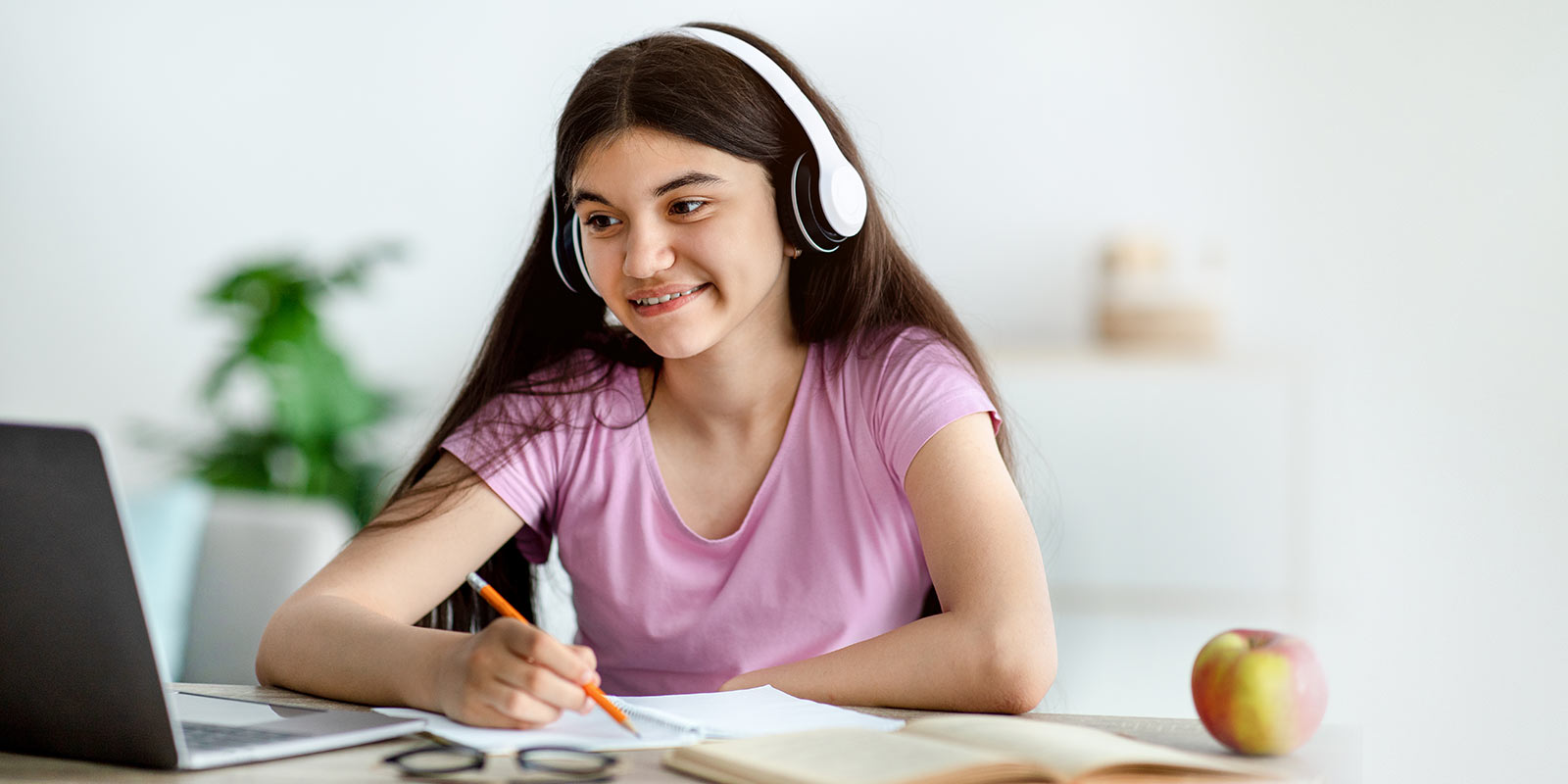 High school female student sitting in front of a laptop with headphones on.